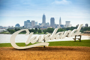 Cleveland skyline with white sign in front saying Cleveland